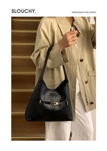 Detail of black woven leather shoulder bag with gold hardware buckle and elegant texture