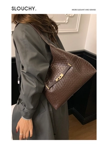 Detail of a dark brown woven leather shoulder bag with a gold twist lock on a slouchy tote