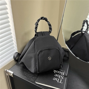 Mochila multifuncional de lona negra con asa de cuerda en contraste y diseño triangular