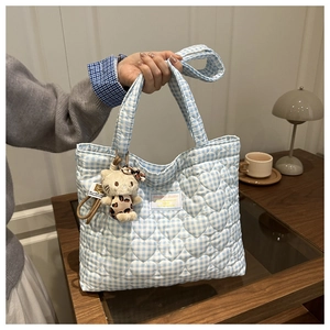 Detalle del bolso tote acolchado de cuadros azules con patrones de corazones y llavero de gato