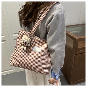 Detalle del bolso tote acolchado de cuadros marrones con un lindo colgante de gato