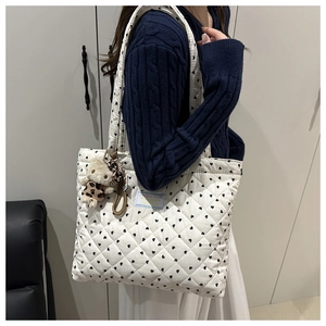 Detalle del bolso tote acolchado blanco con patrones de corazones y un oso de peluche