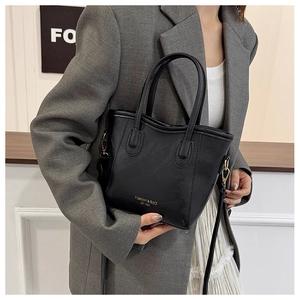Detail of matte black bucket bag showing gold Fashion & BaG lettering and fine hardware
