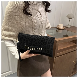 Dettaglio borsa a mano nera leopardata con borchie dorate e cinturino da polso chic