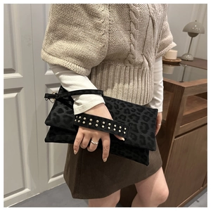 Dettaglio pochette leopardata con manico a borchie dorate e trama animalier strutturata
