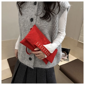 Dettaglio della pochette in camoscio rosso con borchie dorate sul manico largo