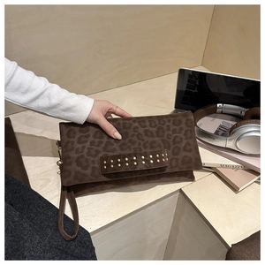 Dettaglio pochette leopardata con borchie dorate e cinturino in un ambiente trendy