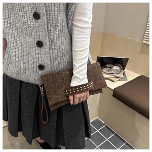 Dettaglio della pochette marrone leopardata con borchie dorate e cinturino da polso