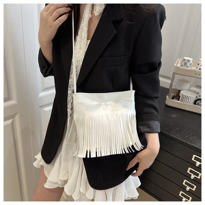 Detail shot of white leather crossbody bag with dense fringe accents and thin shoulder strap