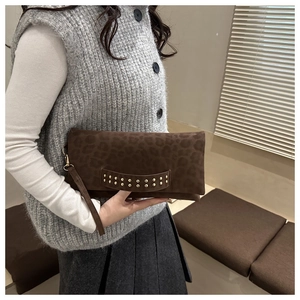 Dettaglio di pochette a busta leopardata marrone scuro con borchie dorate e cinturino