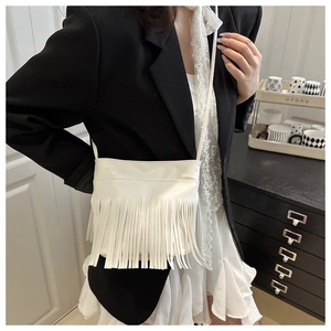 Détail du sac à bandoulière blanc à franges porté par un mannequin en blazer noir