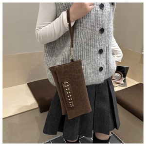 Dettaglio della pochette leopardata con borchie dorate e cinturino su un outfit casual