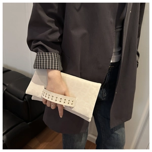 Dettaglio pochette bianco avorio con trama leopardata e borchie in metallo tenuta da modella