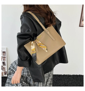 Détail du sac cabas kaki avec foulard en soie, porté par un mannequin en veste de cuir