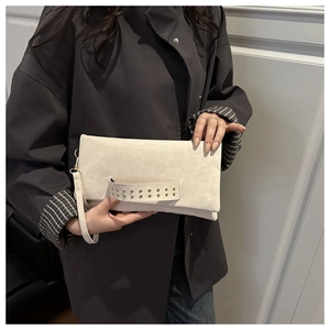Dettaglio della pochette crema leopardata con rivetti dorati e cinturino da polso