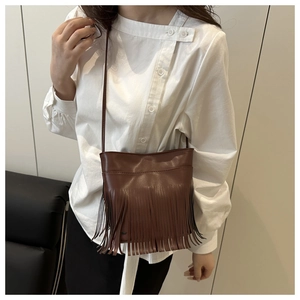 Detail der dunkelbraunen Vintage-Beuteltasche mit modischen Fransen und schmalem Schultergurt