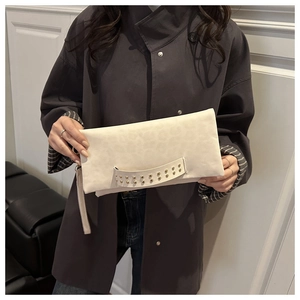 Dettaglio pochette crema con stampa leopardata, borchie dorate e cinturino da polso