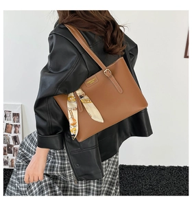 Brown faux leather tote bag detail with floral silk scarf and fashion text print