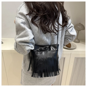 Vue détaillée d'un sac bandoulière noir à franges dans un décor intérieur minimaliste