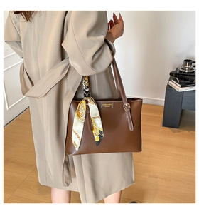 Brown leather tote bag detail with decorative floral silk scarf on shoulder strap