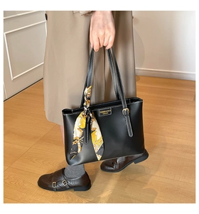 Detail of black leather tote bag with white contrast stitching and printed silk scarf