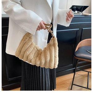 Detail of light camel plush handbag featuring soft pleated texture and woven knot handle