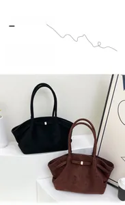 Détail de grands sacs cabas en daim avec boucles dorées en noir et marron