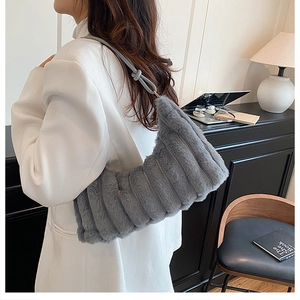 Detail view of a gray faux fur shoulder bag with vertical stripes and slim leather strap