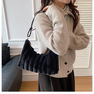 Close-up of black plush shoulder bag with vertical quilted texture and soft faux fur