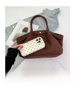 Sac fourre-tout en daim marron comparé à un smartphone montrant sa grande capacité