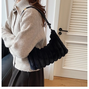 Détail du sac à bandoulière en fausse fourrure noire avec texture plissée et lanière