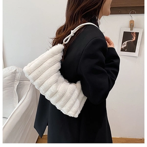 Detail of white plush shoulder bag featuring soft textured fur and stylish knot strap design