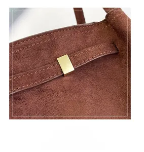 Gros plan du sac en daim marron avec boucle en métal doré et détails de couture
