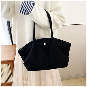Détail du sac cabas noir mat avec boucle dorée et nœud porté à l'épaule