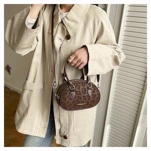 Detail of a brown leopard print Boston bag with Creative Cat text and leather strap