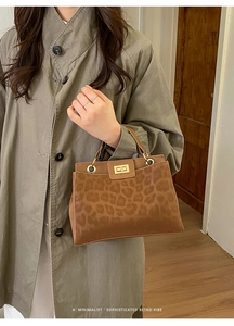 Detail of leopard print bucket bag with gold twist lock and metallic ring handle