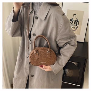 Detail of a brown leopard print boston bag with matte texture on a grey trench coat
