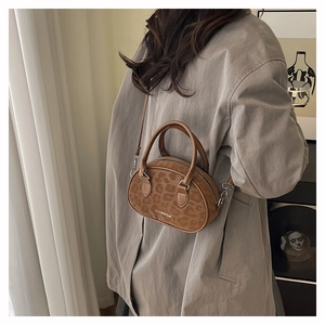Brown leopard print Boston bag styled as a crossbody on a model in a cozy interior