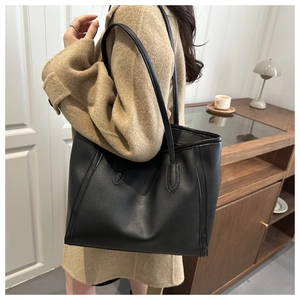 Detailed close-up of large black leather tote bag with elegant stitching on shoulder strap