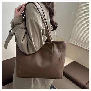 Brown large-capacity tote bag in matte leather featuring vertical decorative stitching
