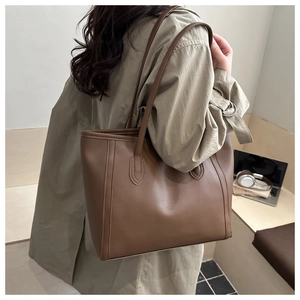 Detail of dark brown leather tote bag showing large capacity and shoulder strap design