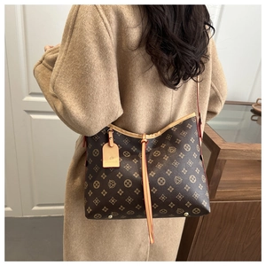 Dettaglio della borsa tote vintage con monogramma e tracolla su un cappotto beige