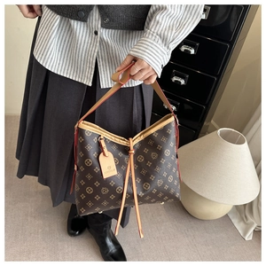 Dettaglio della borsa tote vintage con monogramma in pelle marrone e bordi rossi rifiniti