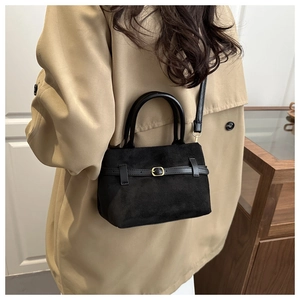 Matte black bucket bag with gold buckle detail worn by model for elegant lifestyle view