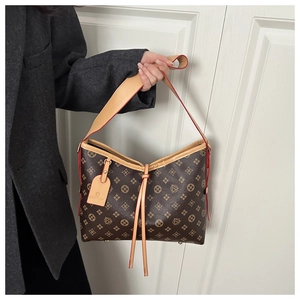 Dettaglio della borsa hobo marrone con monogramma, tracolla in pelle e piedini in metallo