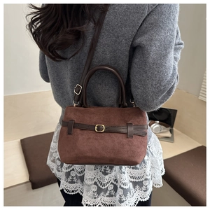 Sac seau en daim marron avec boucle de ceinture, porté par un mannequin en pull gris