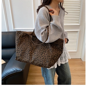 Close-up of leopard print canvas tote bag carried by a model in a stylish interior