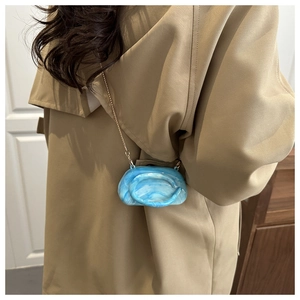 Close-up of a blue marble texture mini crossbody bag with a golden metal chain strap