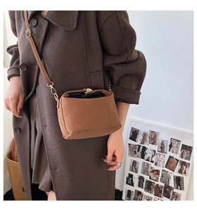 Close-up of caramel brown vintage kiss-lock crossbody bag worn with a wool coat