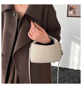 Detail of minimalist beige leather crossbody bag paired with a winter wool coat